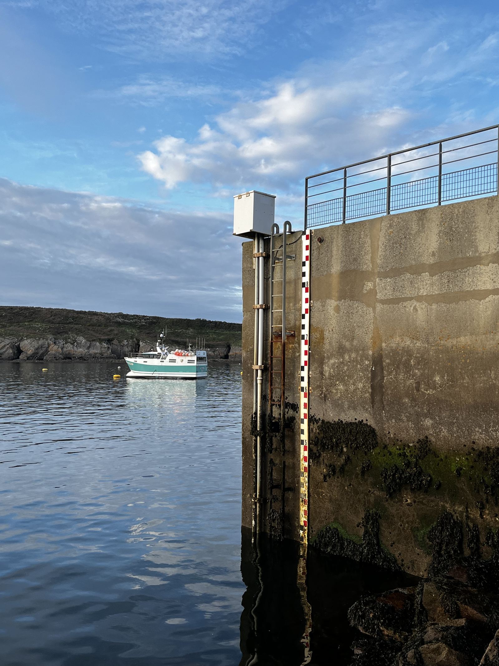 A graduated tide staff on a harbour wall, used to read sea level against a fixed datum — the same principle behind every gauge in the global tide-monitoring network.